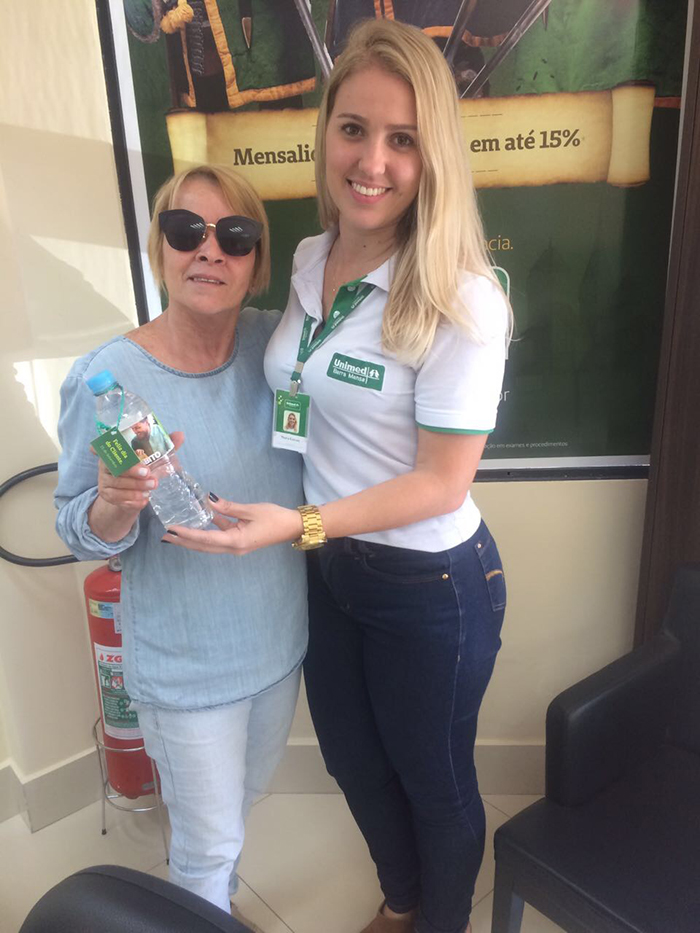 Beneficiária foi presenteada pelo Dia do Cliente por colaboradora com garrafa de água personalizada.