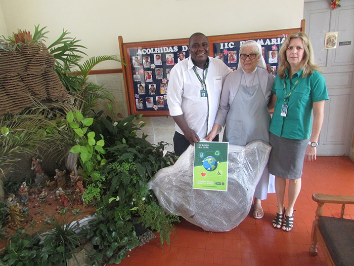 Os colabradores Edmar Bevilaqua e Rita Leme entregam a cadeira de rodas para irmã Dinorah