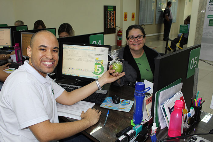 Cliente Unimed recebe maçã verde em ação de incentivo à vida saudável no Dia do Cliente. 