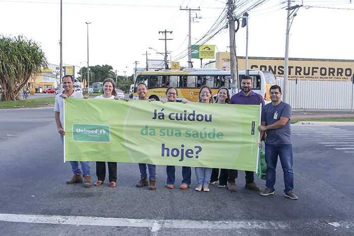 Equipe segurando faixa com mensagem sobre a atenção à saúde